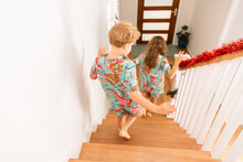 siblings in matching Christmas pyjamas racing downstairs