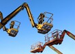 © luca piccini basile - Two aerial working platforms of cherry pickers in front of other two. Blue sky background.