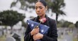 Funeral, death and rose for a woman with a flag at a cemetery in mourning at a memorial service. Sad, usa and an army wife as a widow with a flower in a graveyard feeling the pain of loss or grief