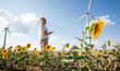 A young woman with a tablet in a field with sunflowers, wind turbines for green energy production, eco-energy, wind turbines