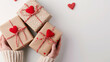 Cadeaux de Saint-Valentin tenus dans des mains féminines sur fond décoré de cœurs