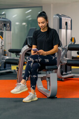 Wall Mural - beautiful young girl in the gym with a phone in her hands watching online training lessons