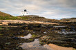 Bamburgh Lighthouse next to Stag Rock.  Also known as Blackrocks Point Lighthouse and part of Harkess Rocks on Bamburgh Beach on the North Sea Shoreline in Northumberland, England