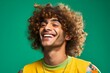 Portrait of a smiling young man with curly hair on a green background