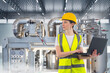 © Grispb - Woman factory engineer. Technologist with laptop in hands. Girl near industrial equipment. Manufactory employee in yellow uniform. Technologist controls industrial equipment. Industrialist woman