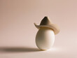 An egg in a cowboy hat on a beige background.