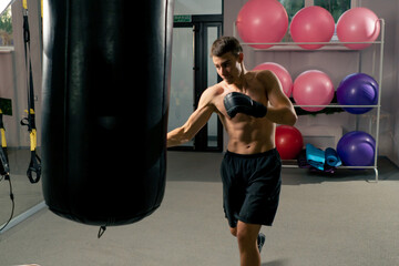 Wall Mural - a boxer concentrates training in the gym in boxing gloves hitting a punching bag strength exercises