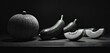  a black and white photo of an eggplant, a melon, and an eggplant sliced in half on a wooden table with a black background.