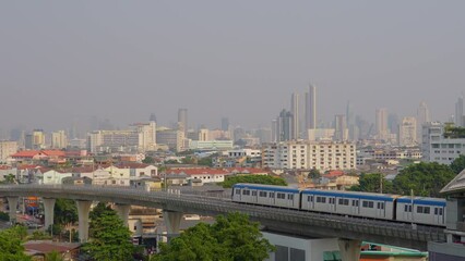 Wall Mural - City metro train carriage departs over an overpass bridge to the central part of the metropolis, tall skyscrapers are visible in the distance