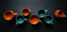  A Group Of Orange And Green Cups Sitting Next To Each Other On A Black Surface With Polka Dots On The Cups And A Polka Dot Dot On The Top Of The Cups.