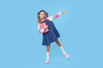 Canvas Print - Smiling schoolgirl with books on light blue background