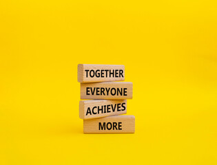 Together Everyone Achieves More symbol. Concept words Together Everyone Achieves More on wooden blocks. Beautiful yellow background. Business concept. Copy space.