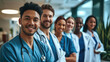 © MP Studio - Diverse group of medical professionals, with a doctor in a white lab coat and stethoscope at the forefront, smiling at the camera.