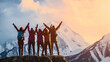 from behind view group of people standing with arms up in front of magical sunset in mountains in success and achievement concepts