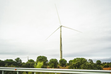 A single wind turbine stands tall against a cloudy sky.