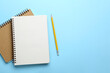 © New Africa - Notebooks and pencil on light blue background, top view. Space for text