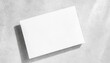 closeup of empty white rectangle poster mockups lying diagonally with soft shadow on neutral light grey concrete background flat lay top view open composition