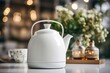  a white tea kettle sitting on top of a table next to a vase of flowers and a cup of coffee.