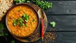 Indian dal. Traditional Indian soup lentils. Indian Dhal spicy curry in bowl, spices, herbs, rustic black wooden background. Authentic Indian dish. Overhead