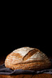 Rustic sourdough wheat bread on a wooden table and dark background. Photo front.