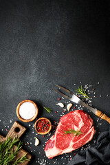 Wall Mural - Raw meat steak. Beef steak with spices on black background. Top view with copy space.