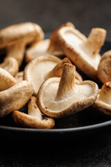 Wall Mural - The fresh shiitake mashrooms on plate on black table.