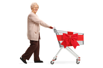 Wall Mural - Full length shot of a senior woman pushing an empty shopping cart with red ribbon bow