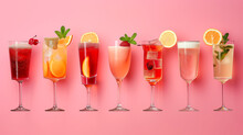 A Variety Of Colorful Cocktails In Elegant Glasses, Garnished With Fruits And Herbs, Lined Up Against A Pink Background