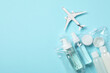 Cosmetic travel kit in plastic bag and toy plane on light blue background, top view with space for text. Bath accessories