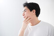 頬を触るアジア系（日本人）男性 爽やかな脱毛やスキンケアのイメージ クローズアップ メンズの美容やビューティーに