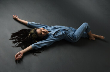 Full length portrait of brunette female asian model wearing casual clothes, double denim jean pants. Isolated on dark studio background with shadows