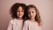 © Ai - Two cute little girls with curly hair posing in studio on pink background
