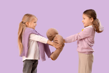 Canvas Print - Cute little girls with teddy bear on lilac background. Childhood cancer awareness concept