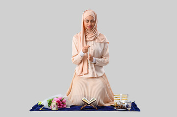 Wall Mural - Muslim woman sitting on prayer mat with prayer beads, Ramadan symbols and Koran on white background