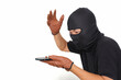 Side view: A man wearing a black t-shirt and balaclava is looking at a smartphone while raising his hand