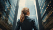 back view of business woman standing in front of a tall skyscraper building in a city