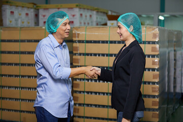 businessman meeting and shaking hands with businesswoman in the beverage factory