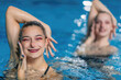 © Microgen - The elegance of a synchronized swimming female duet during their dedicated training session, mastering intricate moves with fluidity and precision