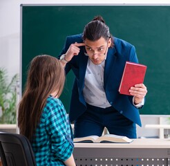 Wall Mural - Young handsome teacher and female student in the classroom