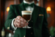 © Keitma - Irish coffee cocktail with an Irish bartender in green suit handing a glass of Irish coffee a cocktail made of whiskey, coffee and cream