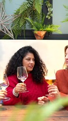 Wall Mural - Three female friends toasting with white wine sitting in a modern colorful cafeteria