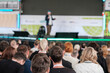 © Anton Gvozdikov - Audience attentively listening to a speaker at a business conference event, with focus on attendees.