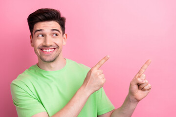 Poster - Photo of young worker positive man wear green t shirt when directing forefingers television channel isolated on pink color background