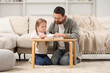 © New Africa - Girl and her godparent reading Bible together at table in room