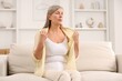 © New Africa - Menopause. Woman suffering from hot flash on sofa at home