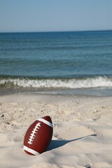 Wall Mural - American football ball on beach. Space for text