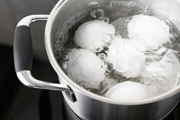 Wall Mural - Chicken eggs boiling in pot on electric stove, closeup
