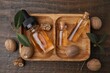 Nutmeg essential oil and nuts on wooden table, flat lay