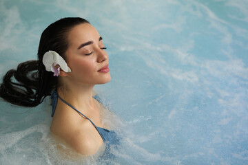 Wall Mural - Beautiful woman with orchid flower in spa swimming pool, space for text