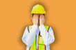 © ฺฺฺBoonterm - Female worker covers her face with her hands have health problems problem of eye irritation from excessive dust and air pollution in construction siteslight orange background.